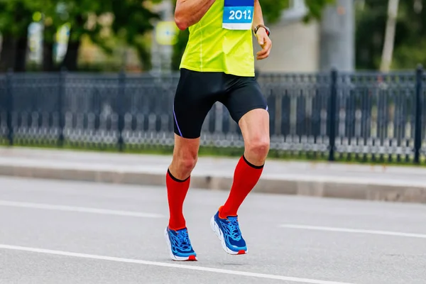 male runner in compression socks run marathon race, bright sportswear for running, timer on athlete hand