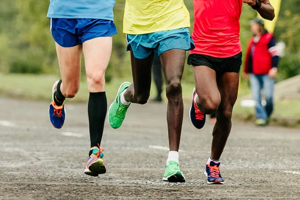 アフリカとヨーロッパの2人のランナーがマラソンを走るフロントビューの脚ジョガーが世界選手権レースを走る — ストック写真