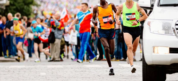 ケニアとヨーロッパを代表する2人のランナーが車の後ろでマラソンを走るジョガーは世界選手権を走る — ストック写真