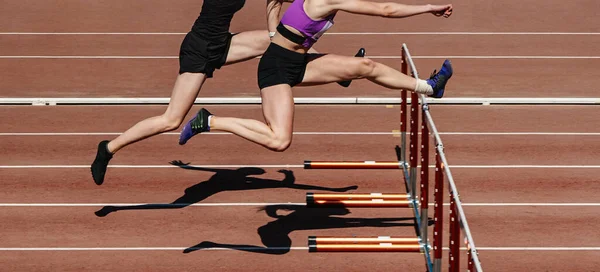 两名女运动员在田径比赛 体育场跑道跨栏 夏季运动会中跑步 — 图库照片