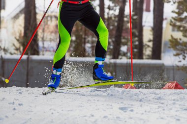 Kayak pistinde koşan kayakçı, kayak ve direklerin altından kar damlaları, kış sporları yarışması.