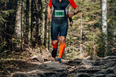 male runner in compression socks running forest trail over stones, summer marathon race clipart