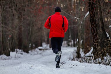 Geri koşan erkek koşucu, soğuk havada karlı ormanda koşan adam.