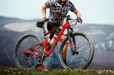Erkek sporcular dağ bisikletleriyle ülkeyi boydan boya geçen bisikletleriyle yokuş yukarı yürüyorlar. Odaklanan bisikletler, Maxxis lastikleri, VaggeSport bisiklet kıyafetleri.