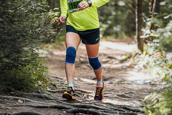 オスランナーはアシックスのショートパンツやランニングシューズで森のトレイルマラソンを走る — ストック写真