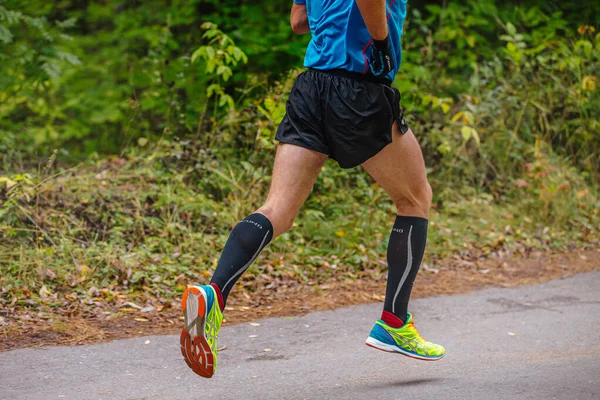 足の男はロードシティパークでマラソンを走る 靴や手袋 水野圧縮ソックスを実行している — ストック写真