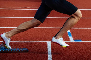 Yakın mesafe koşucusu, kırmızı pistteki başlangıç bloklarından koşmaya başlıyor. Yaz atletizm şampiyonası.