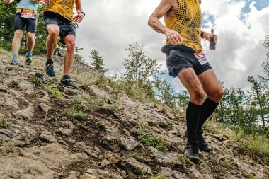 Grup sporcuları dik dağ yamacından aşağı koşuyor, yaz maratonu