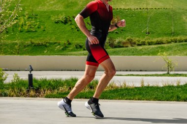 Kenar manzaralı atlet, şehir parkında maraton koşuyor. Yaz sporları etkinliği.