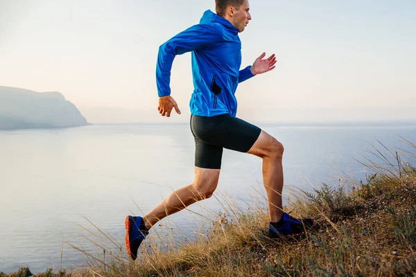 Male Runner Athlete Running Uphill Blue Jacket Black Tights Background — Stock Photo, Image