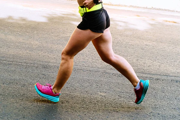 close-up legs female runner running on asphalt road marathon race