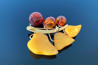 vintage brooch berries and leaves with of amber and brass, made in USSR on dark glossy background clipart