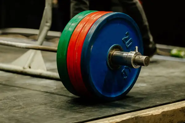 stock image close-up barbell with red, green and blue plates on rubber floor