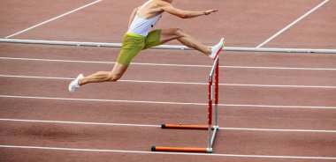 Atlet atletizm maçlarında 400 metre engelli koşuyor.