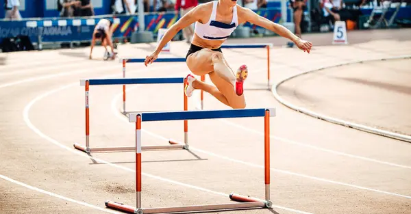 stock image female runner running 400 meters hurdles race in summer athletics championships