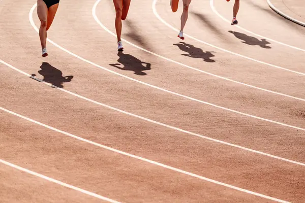 stock image beginning 800-meter race, women legs, shadows on red track stadium