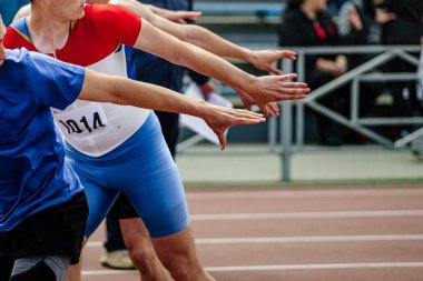 Atletizm müsabakasında bayrağı devretmeyi bekleyen dört el atlet.