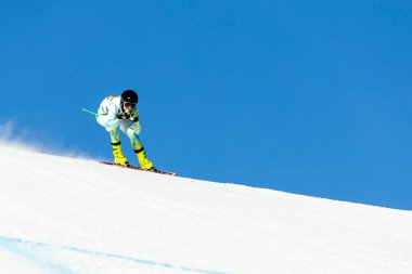 Kazakistan kayak takımındaki kayakçı rekabetçi Alp disiplini sırasında karla kaplı yamaçtan aşağı kayıyor.