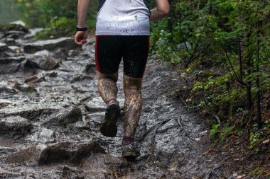 Orman maratonu sırasında çamurlu taş koşusu yapan bir sporcu.