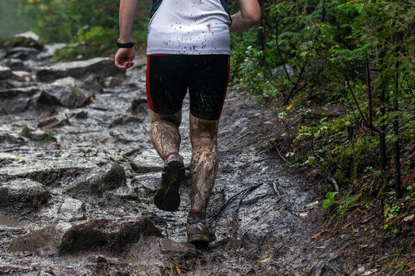 Спортсмен, бегущий по грязным камням во время лесного марафона