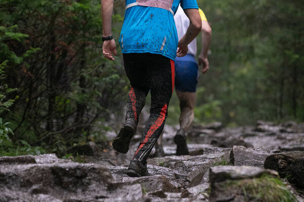 Спортсмен, бегущий по грязным камням во время марафона под ливнем
