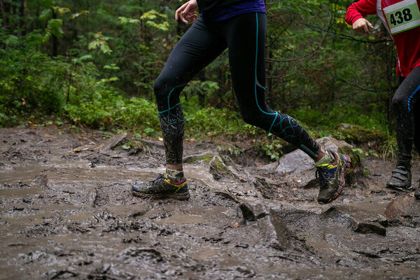 Ноги спортсменки бегают по грязи и камням во время марафонской гонки