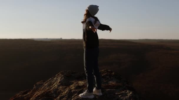 Yüksek Sarp Kayalıklardaki Turist Kadın Kollarını Yanlara Açmış Gün Batımında — Stok video