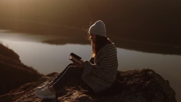 女人打开圣经 一个女孩在露天阅读圣经 在日落时在山顶上学习上帝的话语 从圣经中寻找真理 — 图库视频影像