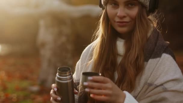 年轻美丽女子的特写镜头将热饮茶从热水瓶倒入杯子 并主动提供给接线员 然后独自饮酒 享受站在秋天里美丽的景色 高质量的4K镜头 — 图库视频影像