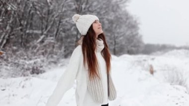 young pretty woman girl in a hat walks through a snowy field in the forest, circling, smiling at the camera, silence, winter frosty Christmas forest, snowfall, magical landscape. High quality 4k footage