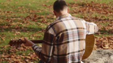 A young man takes a photo of a beautiful autumn nature with a view of a lake and a park with his phone. Walking in the park alone, admiring the beauty of autumn nature. High quality 4k footage