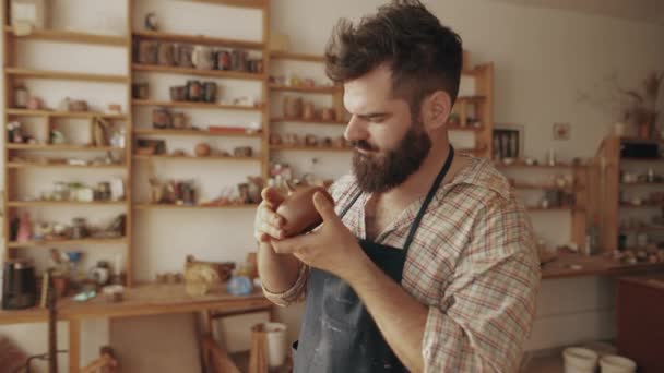 Jonge Bebaarde Mannelijke Pottenbakker Onderzoekt Zijn Werkpot Met Deksel Pottenbakkerij — Stockvideo