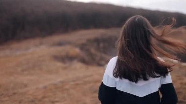 Young smiling woman runs to the top of the mountain peak of the edge of the cliff, raises her hands in the air, and jumps happy and drunk with life, youth and happiness