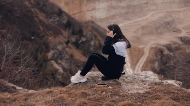 Young Attractive Woman Sits Edge Cliff Canyon Listens Music Headphones — Stok video