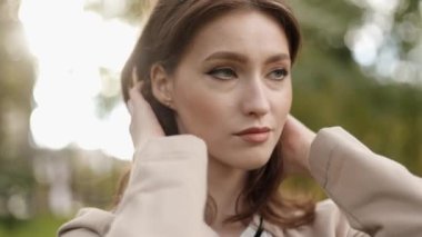 Close up portrait of relaxed woman face breath fresh clean air outdoors enjoying nature weather feels good in park. brunette woman fixes her hair, coquettish, flirting