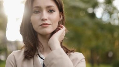 Portrait of a Gorgeous Dark Haired Woman Looking Charmingly while Standing in the city park in business clothes.