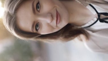 Happy young woman making video call on mobile phone camera. Vertical video view. Face of attractive woman having conversation through video conferencing app on mobile phone, nodding in approval. 