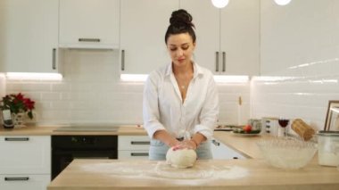 Pizza için hamur yoğuran mutlu genç bir kadın evde hamur işi pişiriyor, gülümseyen bir ev kadını modern mutfakta tek başına yemek pişiriyor pasta veya el yapımı kurabiyeler hazırlıyor.
