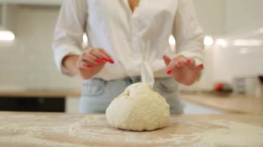 close-up of a woman's hands kneading the dough while tossing in the kitchen at home