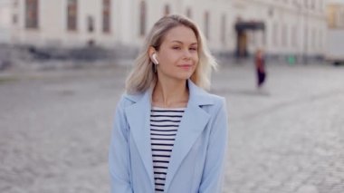Close up portrait of stylish blonde young woman lady girl smiling at camera standing on city street in sunlight