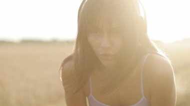 Young pretty female athlete catching her breath after a jogging workout outdoors in the morning at sunrise in the sunlight