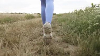 Close up of female legs running on field road outdoors at dawn in summer, concept of healthy running and outdoor exercise
