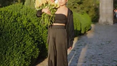 Close up portrait of beautiful pretty slim woman lady in stylish suit with huge bouquet of autumn flowers in sunlight