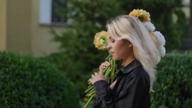 Side view Stylish young elegant pretty cute girl model woman blonde walking in the park holding a big bouquet of flowers on a sunny autumn day