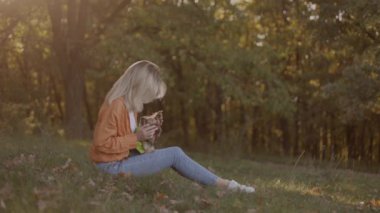 Side view of happy blonde girl sitting on lawn face to face playing with her yorkshire terrier dog outdoors in autumn park people happy joyful dog lifestyle with dog cute animal together