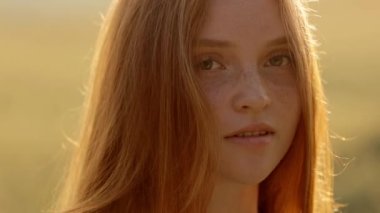 Güzel güzel bir kadın kameraya bakarken gözlerini açar. Güzel yüzünde çilleri olan çekici bir kız. Çekici görünümlü kızıl saçlı bir kadın.