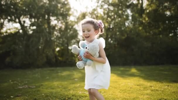Mała Dziewczynka Trzyma Pluszowego Misia Leży Plecach Śmieje Się Głośno — Wideo stockowe