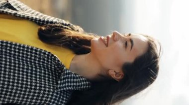 Dağda doğanın tadını çıkaran bir kadının portresi. Çekici bir kadın ileriye bakar ve sonra kameraya bakar ve gülümser. Rüzgar saçı savurur. Mutlu görünüş, özgürlük hissi. Dikey video yönelimi