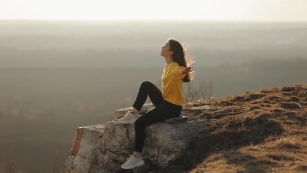 Μια Νεαρή Γυναίκα Ένα Κίτρινο Πουλόβερ Κάθεται Στην Άκρη Ενός — Αρχείο Βίντεο