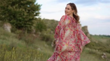 Kamera, şık elbiseli, genç ve güzel bir hipster kızı takip ediyor. Nehrin arka planında uçurumun tepesinde yürüyor. Kameraya gülümsüyor, mutlu ve sarhoş bir şekilde poz veriyor.